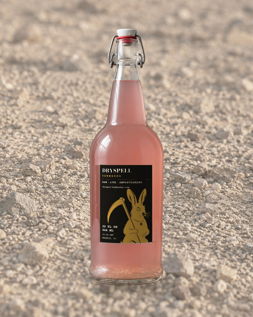 Dryspell 32 oz swing-top bottle, pale pink kombucha, on desert