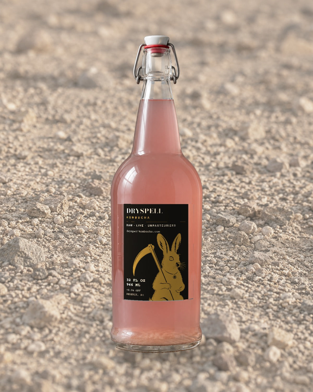 Dryspell 32 oz swing-top bottle, pale pink kombucha, on desert